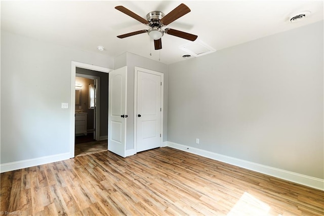 unfurnished bedroom with baseboards, light wood-style flooring, ceiling fan, and attic access