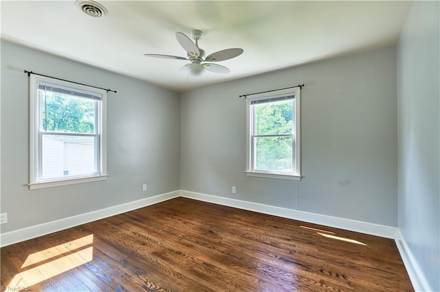 spare room featuring plenty of natural light, dark wood finished floors, and baseboards