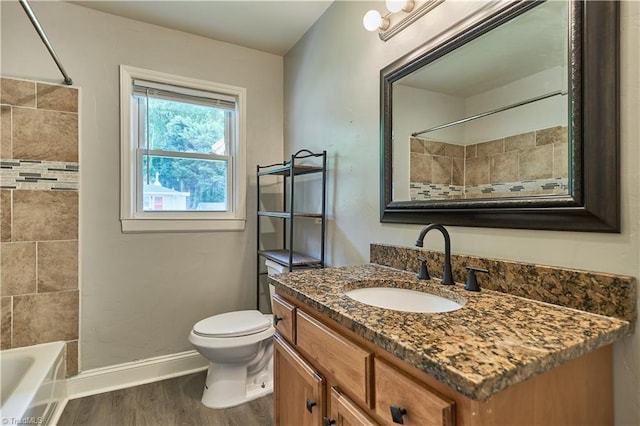 full bath featuring baseboards, wood finished floors, toilet, vanity, and bathtub / shower combination