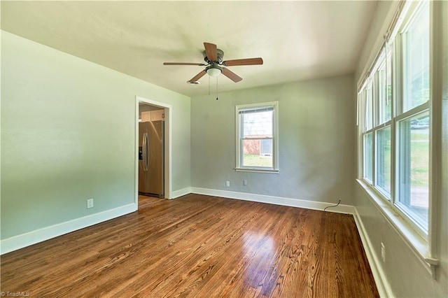 unfurnished room featuring baseboards, dark wood-type flooring, and a ceiling fan