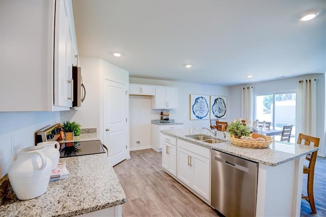 kitchen featuring white cabinetry, stainless steel appliances, a center island with sink, and light wood-type flooring