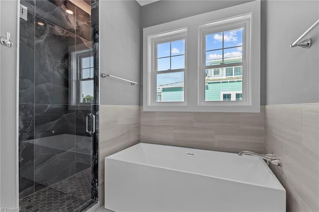 bathroom featuring separate shower and tub and tile walls