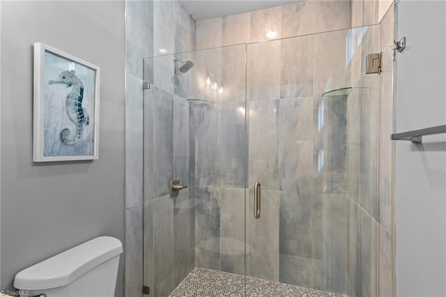 bathroom with a shower with shower door and toilet