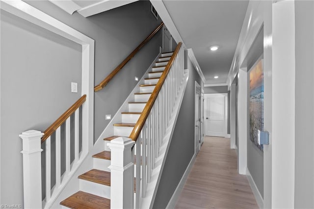 stairway with wood-type flooring and ornamental molding