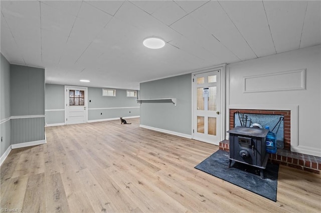 basement with light hardwood / wood-style flooring and a wood stove