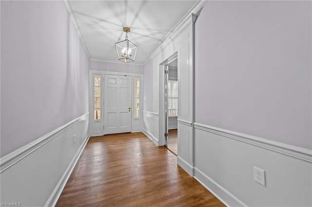 foyer entrance featuring ornamental molding, wood-type flooring, and an inviting chandelier