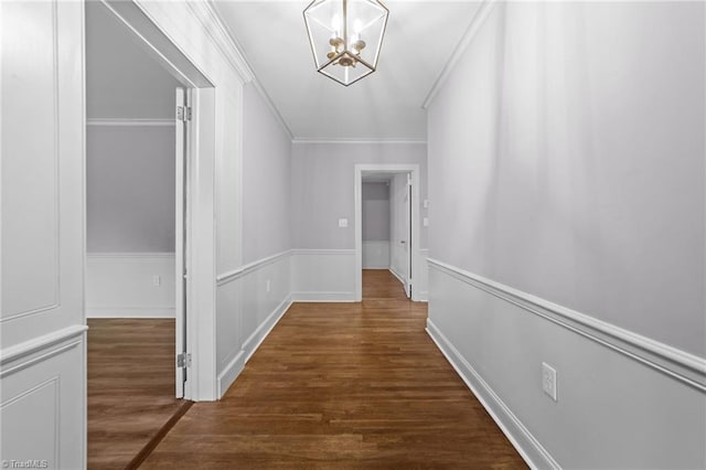 hallway with ornamental molding, dark hardwood / wood-style floors, and a chandelier