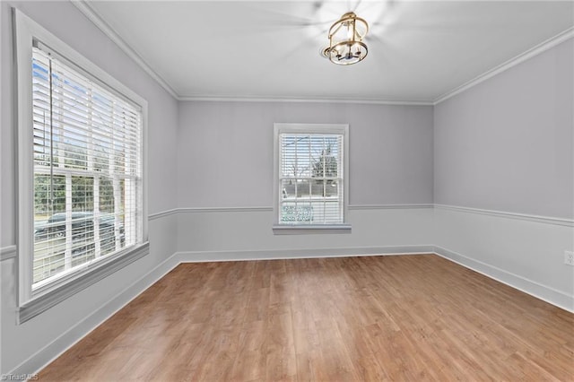 empty room with crown molding, an inviting chandelier, and light hardwood / wood-style flooring