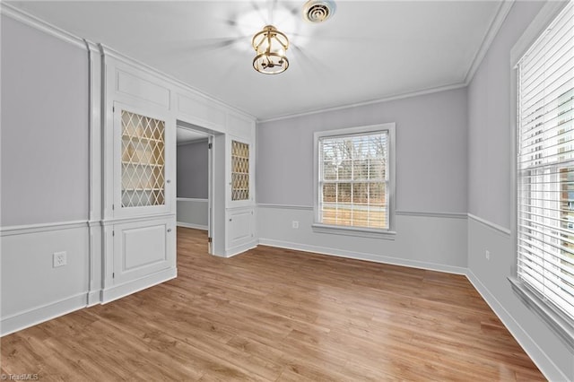 empty room with ornamental molding and light wood-type flooring