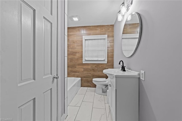 bathroom with toilet, vanity, wooden walls, and a tub