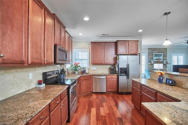 kitchen featuring a sink, ornamental molding, dark wood-type flooring, appliances with stainless steel finishes, and pendant lighting