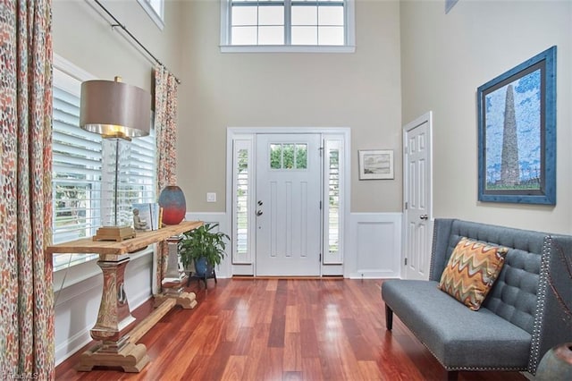 entryway featuring a high ceiling, wood finished floors, and wainscoting