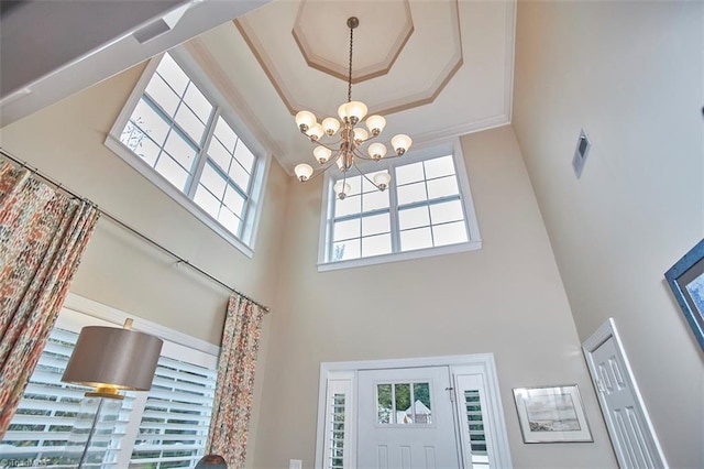 foyer entrance with a notable chandelier, a high ceiling, and ornamental molding