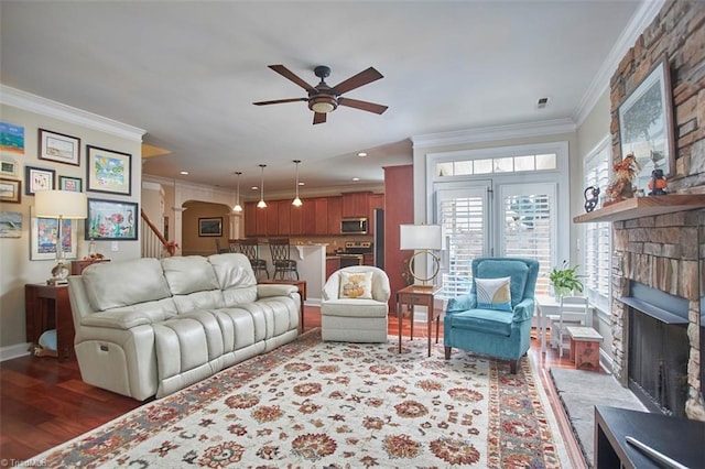 living area featuring wood finished floors, a fireplace, arched walkways, ornamental molding, and stairs