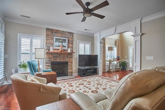 living area with a healthy amount of sunlight, crown molding, ornate columns, and wood finished floors