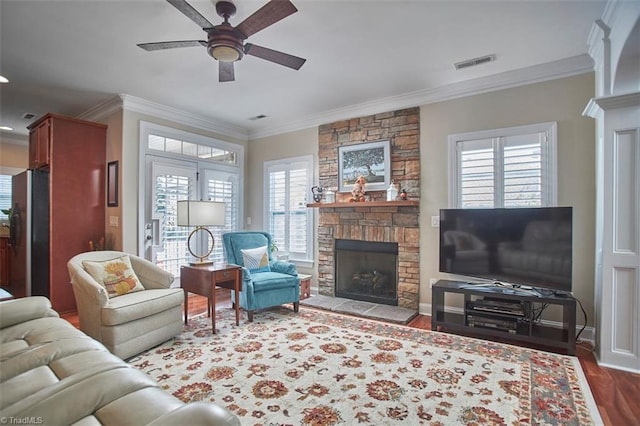 living area featuring visible vents, ornamental molding, a ceiling fan, dark wood finished floors, and a fireplace