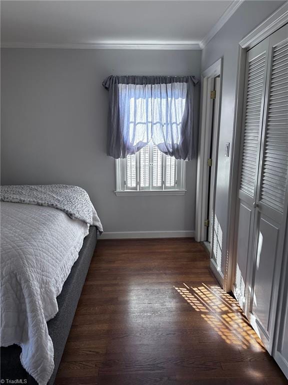 bedroom featuring dark hardwood / wood-style flooring, crown molding, and a closet