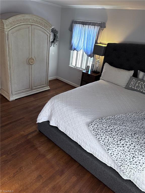 bedroom with dark wood-type flooring and ornamental molding