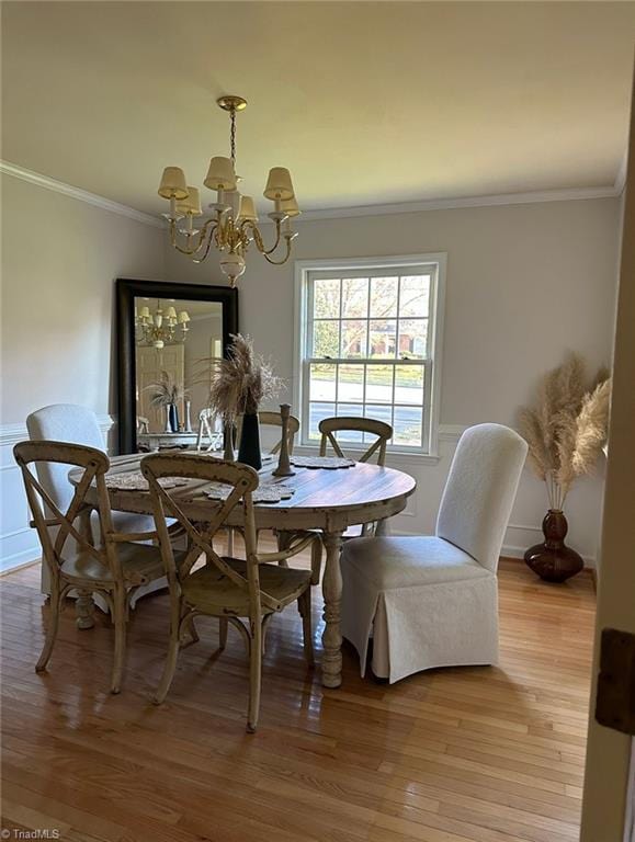 dining room with hardwood / wood-style flooring, ornamental molding, and an inviting chandelier