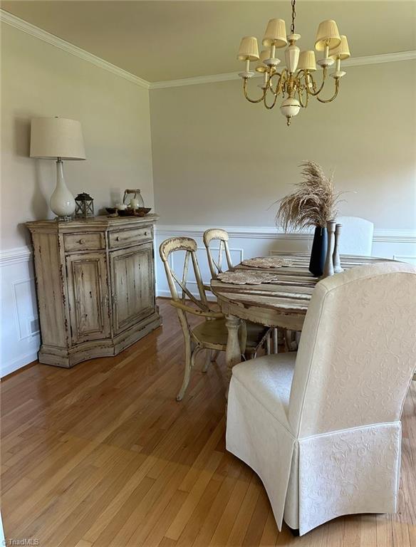 dining area with hardwood / wood-style flooring, a notable chandelier, and ornamental molding