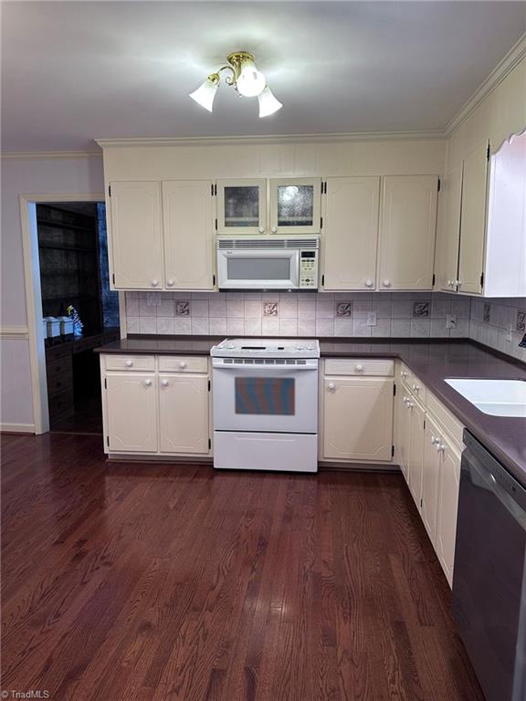 kitchen with white appliances, dark hardwood / wood-style floors, white cabinetry, and tasteful backsplash