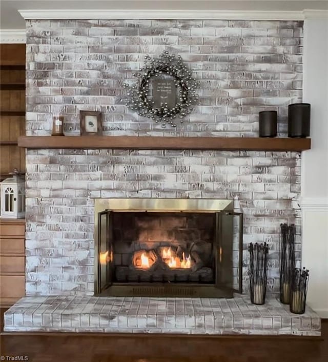 interior details featuring ornamental molding and a brick fireplace