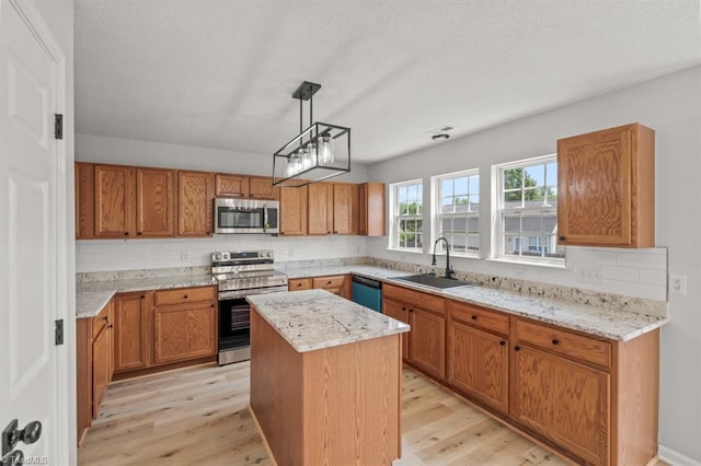 305 Apple Ridge Rd, Greensboro, NC 27406 - kitchen with appliances with stainless steel finishes, decorative backsplash, light wood-style floors, a kitchen island, and brown cabinets