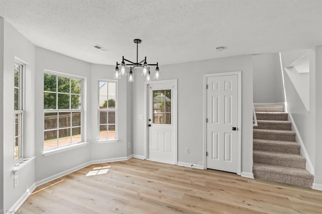 305 Apple Ridge Rd, Greensboro, NC 27406 - unfurnished dining area with light wood finished floors, a chandelier, stairs, and a textured ceiling