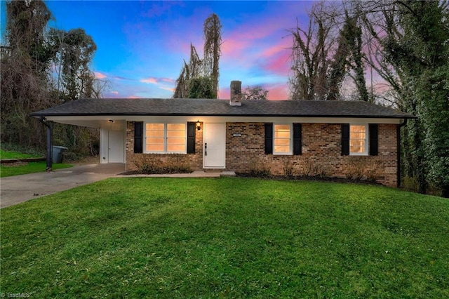 ranch-style home with a yard, an attached carport, brick siding, and driveway