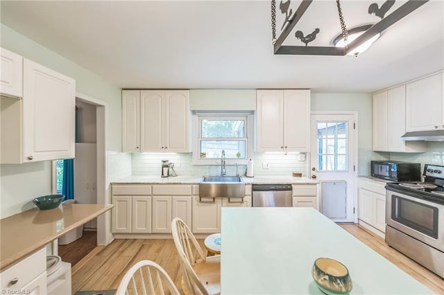 kitchen with stainless steel appliances, a sink, light wood-style flooring, and plenty of natural light