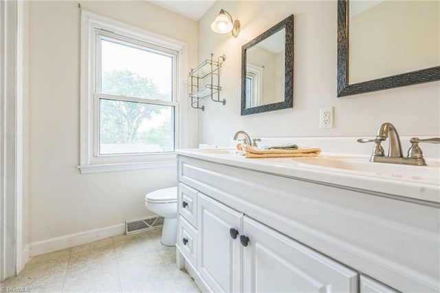 bathroom featuring baseboards, toilet, and double vanity