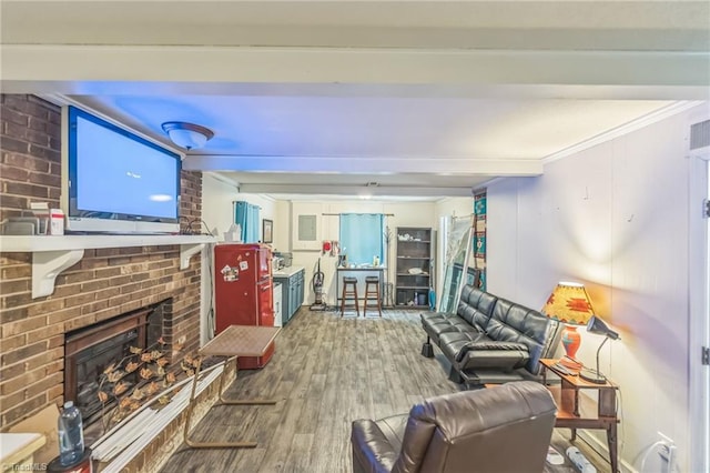 living room featuring wood finished floors, beam ceiling, and a brick fireplace