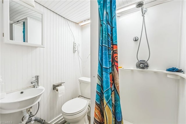 bathroom with curtained shower, toilet, and a sink
