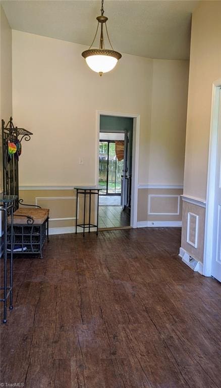 empty room with wood finished floors, wainscoting, and a decorative wall