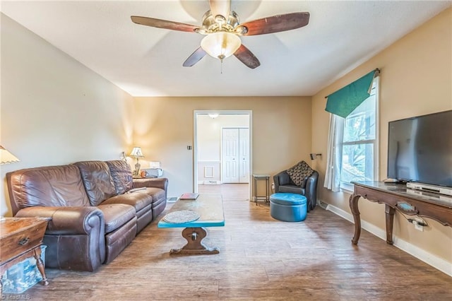 living room with wood finished floors, a ceiling fan, and baseboards