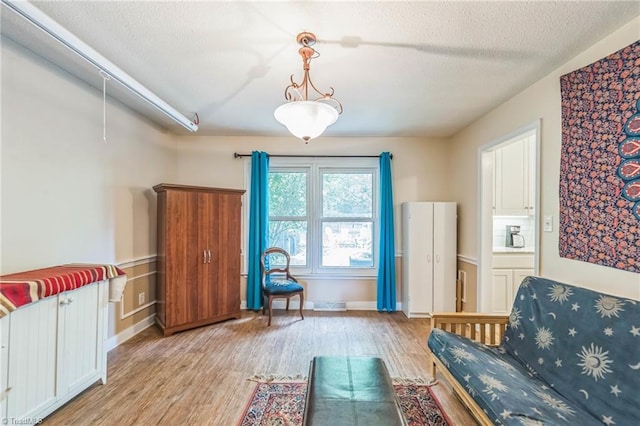 living area with light wood finished floors, a textured ceiling, and baseboards
