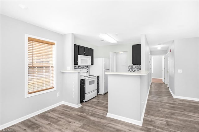 kitchen with white appliances, a healthy amount of sunlight, kitchen peninsula, and backsplash