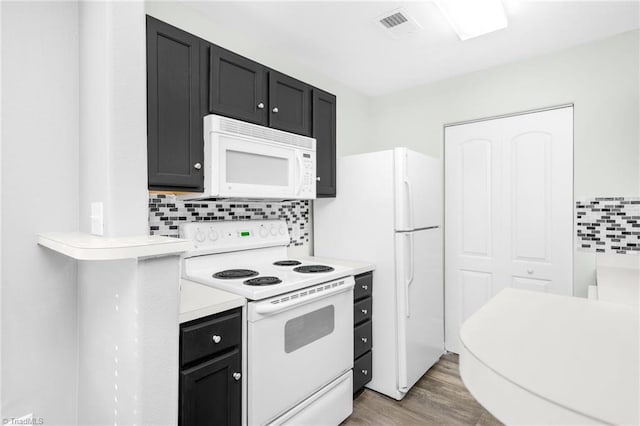 kitchen with tasteful backsplash, hardwood / wood-style floors, and white appliances