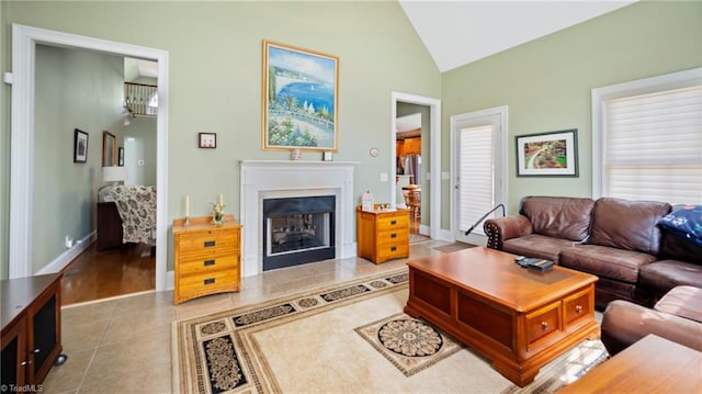 living area with light tile patterned flooring, high vaulted ceiling, baseboards, and a fireplace