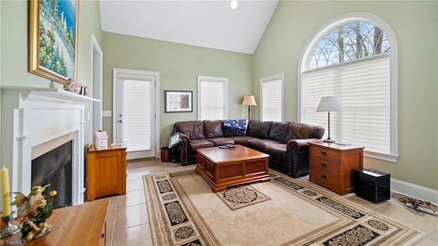 living area featuring light tile patterned flooring, high vaulted ceiling, and a fireplace