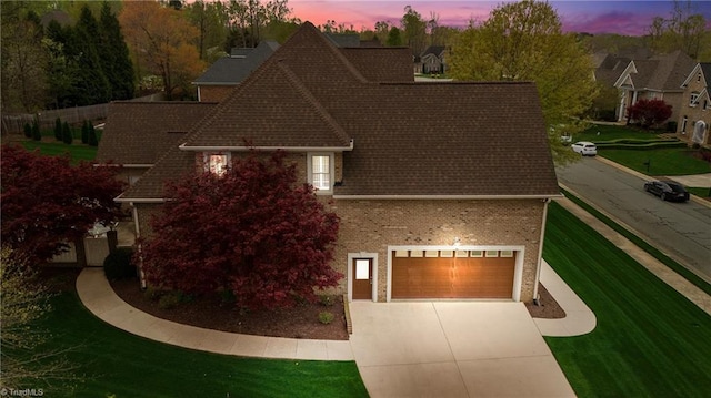 exterior space with brick siding, concrete driveway, and roof with shingles