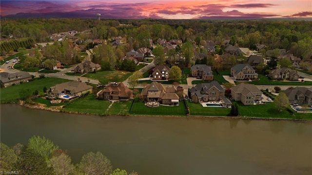 aerial view at dusk featuring a water view and a residential view