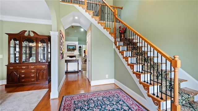 foyer featuring stairway, crown molding, baseboards, a towering ceiling, and wood finished floors
