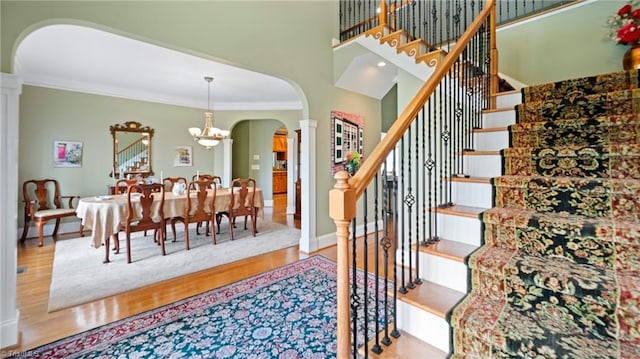stairway featuring ornamental molding, arched walkways, decorative columns, and wood finished floors