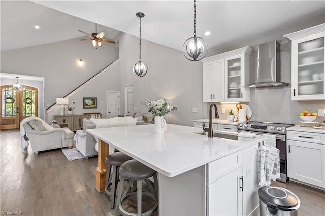 kitchen with wall chimney exhaust hood, white cabinetry, a kitchen bar, and stainless steel electric stove