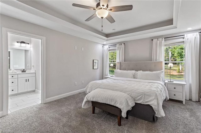 bedroom featuring ceiling fan, light colored carpet, ensuite bath, and multiple windows