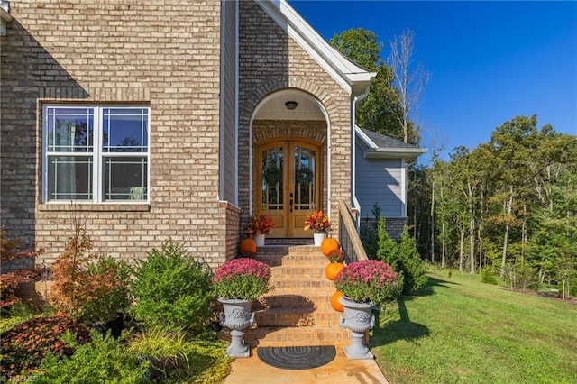 view of exterior entry with french doors and a lawn