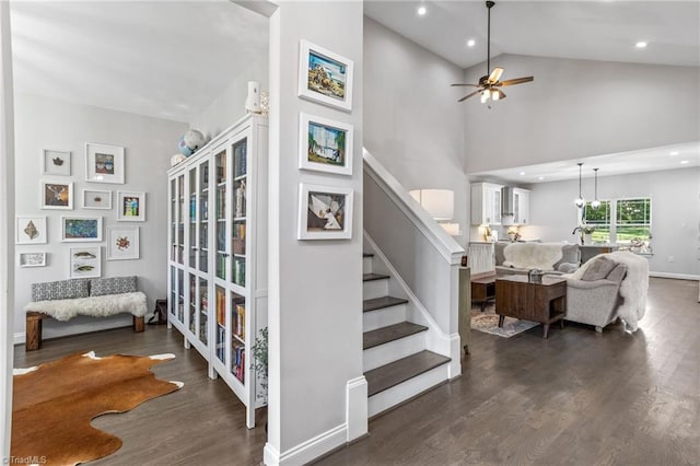 stairway with high vaulted ceiling, ceiling fan, and hardwood / wood-style floors