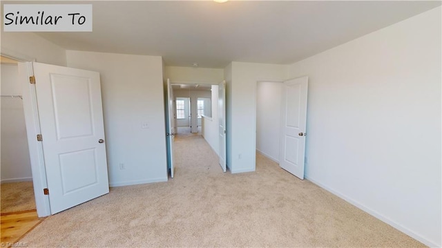 unfurnished bedroom featuring carpet floors, baseboards, a walk in closet, and a closet