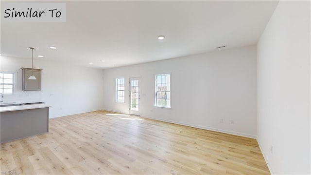 unfurnished living room featuring plenty of natural light, light wood-style flooring, baseboards, and recessed lighting